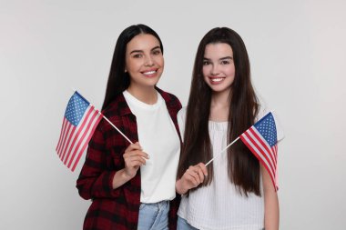 4 Temmuz - ABD 'nin Bağımsızlık Günü. Beyaz arka planda Amerikan bayrakları olan mutlu kadın ve kızı