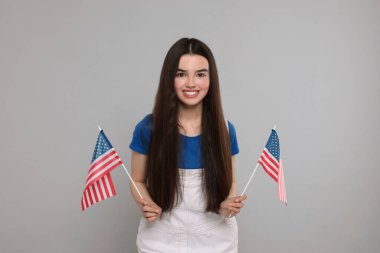 4 Temmuz - ABD 'nin Bağımsızlık Günü. Gri arka planda Amerikan bayrakları olan mutlu kız.