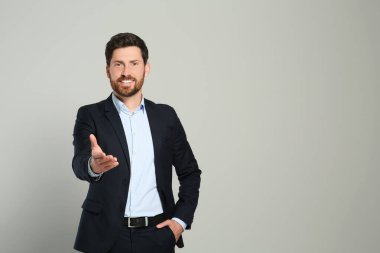 Gri arka planda güzel takım elbiseli yakışıklı bir emlakçı. Mesaj için yer var.