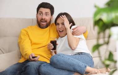 Korkmuş çift evdeki kanepede televizyon izliyor.