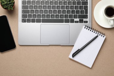 Modern dizüstü bilgisayar, defter ve kahve fincanı bej masada, düz yerde. Metin için boşluk