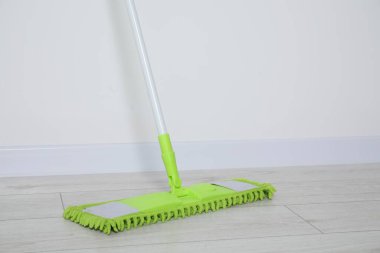 Kapalı alandaki duvarın yanında plastik saplı paspas. Metin için boşluk