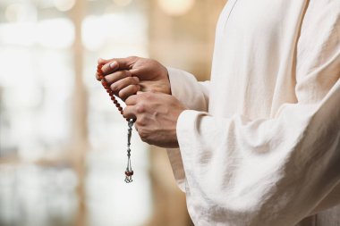 Misbaha 'lı Müslüman bir adam bulanık arka planda dua ediyor, yakın plan. Metin için boşluk