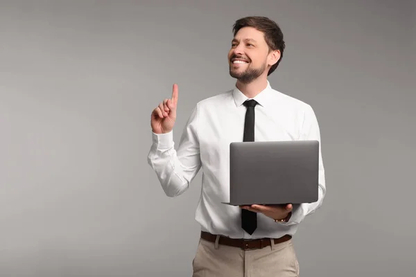 灰色の背景にノートパソコンを持つ幸せな男 テキストのスペース — ストック写真