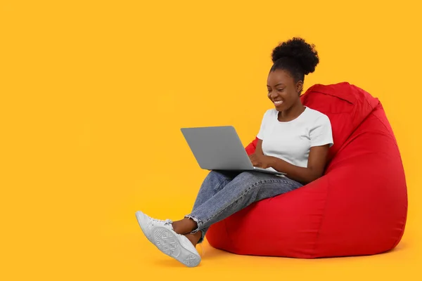 Όμορφη Νεαρή Γυναίκα Φορητό Υπολογιστή Κάθεται Καρέκλα Beanbag Φόντο Πορτοκαλί — Φωτογραφία Αρχείου