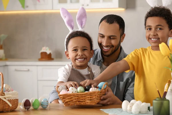 stock image Happy African American father and his cute children with Easter eggs at table in kitchen