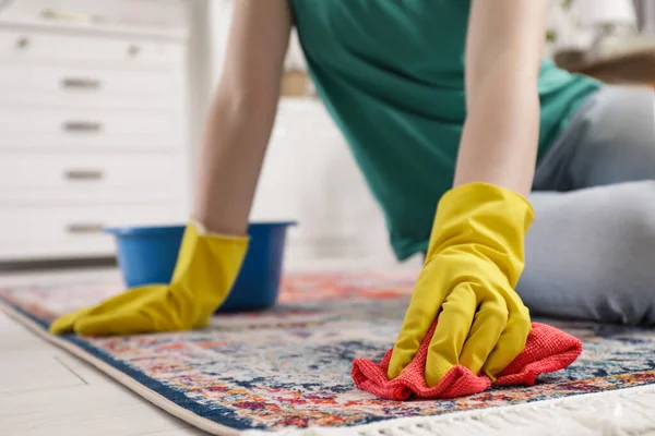 穿着橡胶手套的女人在室内用抹布清洁地毯 — 图库照片