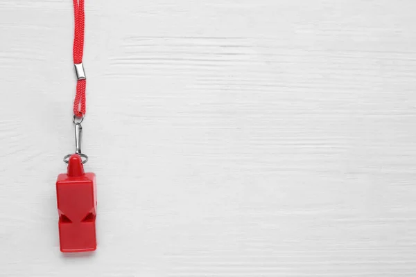 stock image One red whistle with cord on white wooden table, top view. Space for text