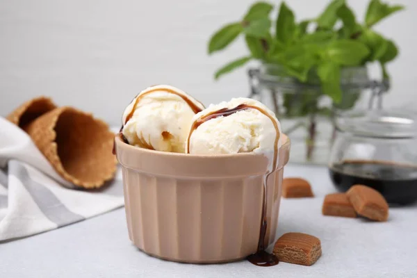 stock image Scoops of ice cream with caramel sauce and candies on light grey table, closeup