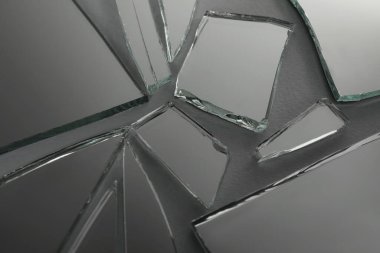 Shards of broken mirror on dark grey background, closeup clipart