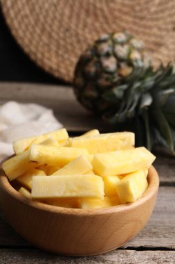 Tahta masadaki kasedeki lezzetli olgun ananas parçaları, yakın plan. Metin için boşluk