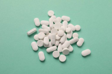 Yeşil arka planda beyaz haplar yığını.