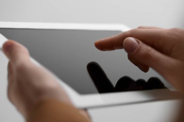Açık gri arka planda modern tablet kullanan kadının yakın görüntüsü