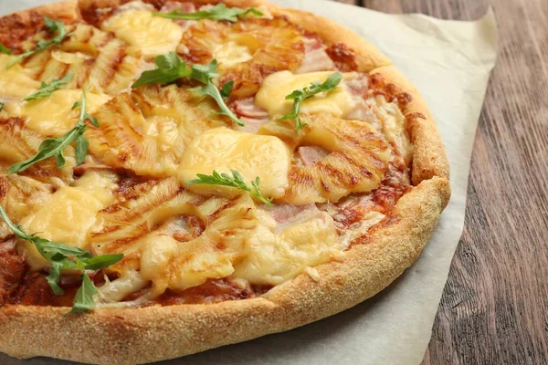 Delicious pineapple pizza with arugula on table, closeup