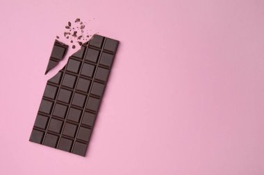 Pembe arka planda kırılmış siyah çikolata. Metin için boşluk