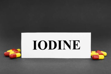 Kelime iyotlu kart ve siyah arka planda bir yığın hap.