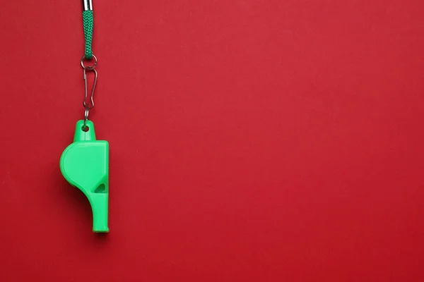 stock image One green whistle with cord on red background, top view. Space for text