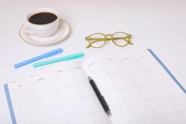 Offener Monatsplan Kaffee Gläser Und Schreibwaren Auf Weißem Hintergrund — Stockfoto