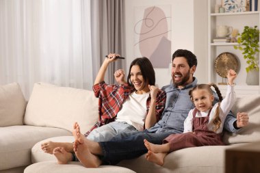 Mutlu aile evdeki kanepede televizyon izliyor, mesaj için yer var.