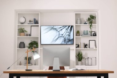 Televizyonun yanında bilgisayar olan rahat bir iş yeri. İç tasarım