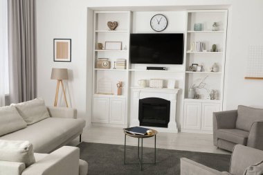 Mobilyaları, dekoratif şöminesi ve televizyonu olan rahat bir oda.