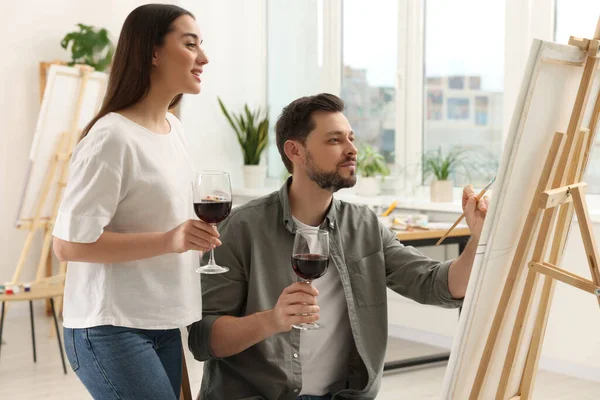 stock image Artist and her student with glasses of wine having painting class in studio. Creative hobby