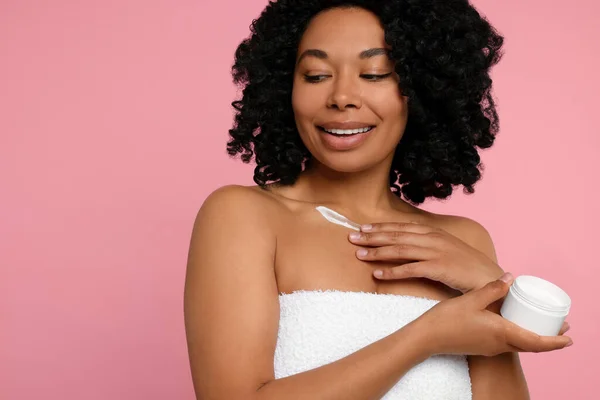 stock image Young woman applying cream onto body on pink background. Space for text