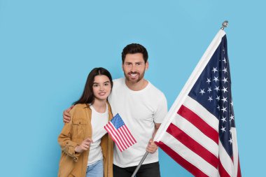 4 Temmuz - ABD 'nin Bağımsızlık Günü. Mutlu adam ve kızı açık mavi arka planda Amerikan bayrakları taşıyorlar.