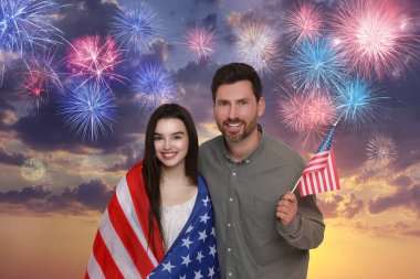 4 Temmuz - Amerika 'nın Bağımsızlık Günü. Mutlu baba ve kızı ABD bayraklarıyla havai fişeklerle gökyüzüne karşı