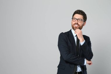 Gri arka planda güzel takım elbiseli yakışıklı bir emlakçı. Mesaj için yer var.