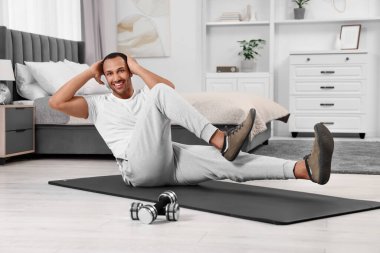 Adam evde spor paspası üzerinde sabah egzersizi yapıyor.