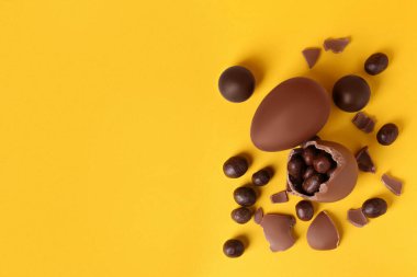 Sarı arka planda şekerli tam ve kırılmış çikolatalı yumurtalar. Metin için boşluk