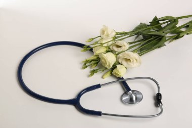 Beyaz arka planda steteskop ve Eustoma çiçekleri. Mutlu Doktor Günleri.