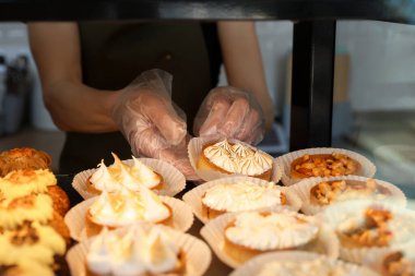 Satıcı pastanede vitrinden lezzetli tart alıyor, yakın plan.