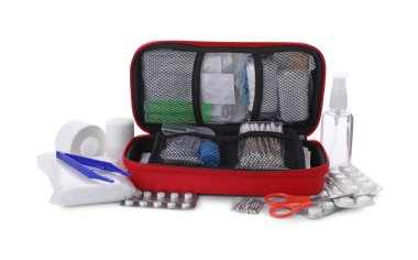 İlk yardım çantası, makas, iğne, pamuk tokaları, haplar, plastik forseps, el dezenfektanı, tıbbi alçı ve elastik bandaj beyaz üzerine izole edilmiş.