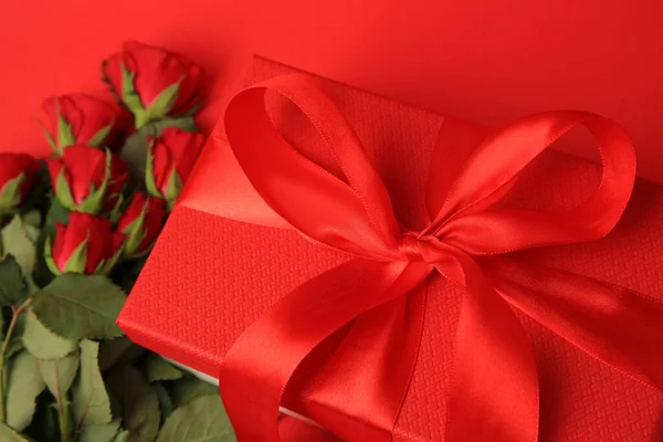 Schöne Geschenkschachtel Mit Schleife Und Rosen Auf Rotem Hintergrund Nahaufnahme — Stockfoto
