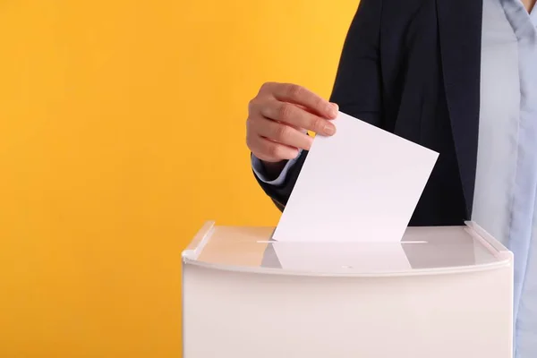 Frau Legt Ihre Stimme Die Wahlurne Auf Orangefarbenem Hintergrund Nahaufnahme — Stockfoto