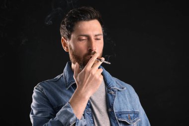 Siyah arka planda sigara içmek için sigara tutacağı, metin için boşluk kullanan adam