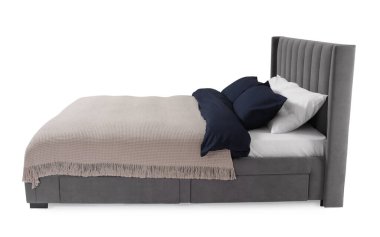 Beyaz arka planda çarşafları olan rahat gri yatak.