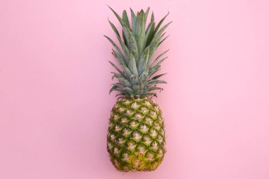 Pembe arka planda tam olgun ananas, üst manzara.