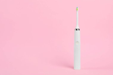 Pembe arkaplanda elektrikli diş fırçası, metin için boşluk