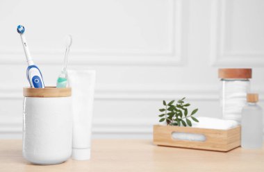 Elektrikli diş fırçaları, ahşap masa üzerinde bir tüp macun ve tuvalet malzemeleri.