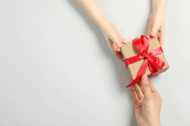 Anne çocuğuna beyaz arka planda hediye paketi veriyor. Metin için boşluk