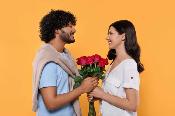 国際的なデート 黄色の背景にバラの花束を持つ幸せなカップル — ストック写真