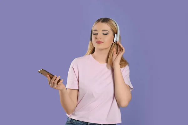 Όμορφη Γυναίκα Στα Ακουστικά Απολαμβάνοντας Μουσική Και Κρατώντας Smartphone Βιολετί — Φωτογραφία Αρχείου