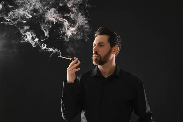 黒い背景でタバコを吸うためにタバコホルダーを使用して男 — ストック写真