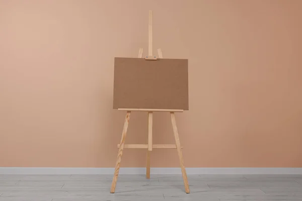 stock image Wooden easel with blank board near beige wall indoors