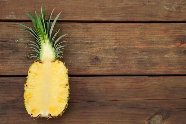 stock image Half of ripe pineapple on wooden table, top view. Space for text