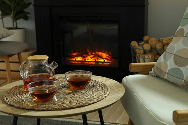 居心地の良いリビングルームでスタイリッシュな暖炉の近くのコーヒーテーブルの上にティーポットとドリンクのカップ インテリアデザイン — ストック写真