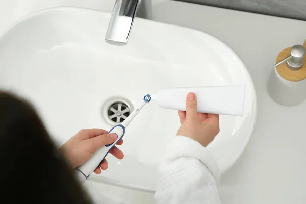 Frau Drückt Zahnpasta Aus Tube Auf Elektrische Zahnbürste Über Waschbecken — Stockfoto